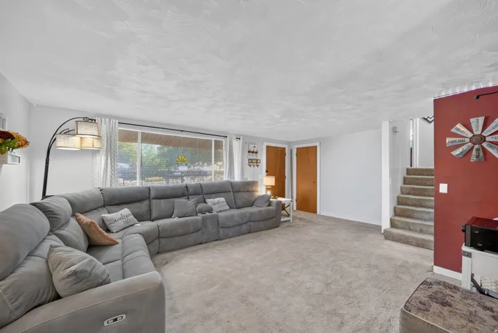 Carpeted flooring, large window with ample natural light, and a stairway with carpeted treads