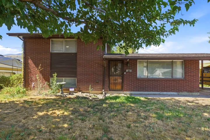 Brick exterior featuring a covered entry and a large front window