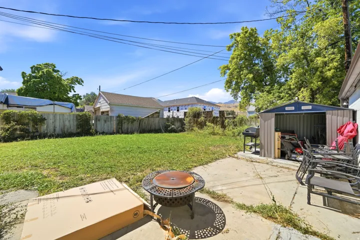 Expansive backyard featuring a lush lawn, concrete patio, and a metal storage shed