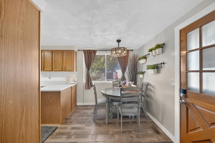 Wood-finish flooring, wood cabinetry with white countertops, a window with natural light, and a decorative ceiling light fixture