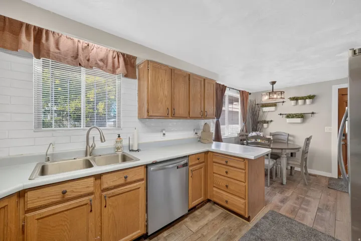 Kitchen featuring wood cabinetry, white countertops, stainless steel appliances, and a subway tile backsplash