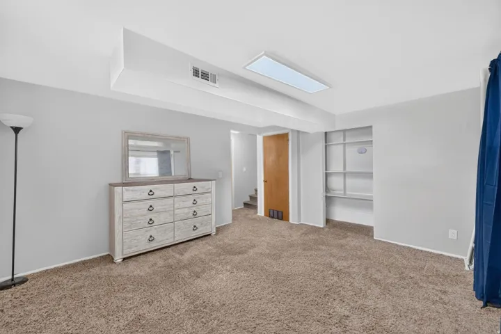 Recessed lighting, built-in shelving, and neutral carpeting
