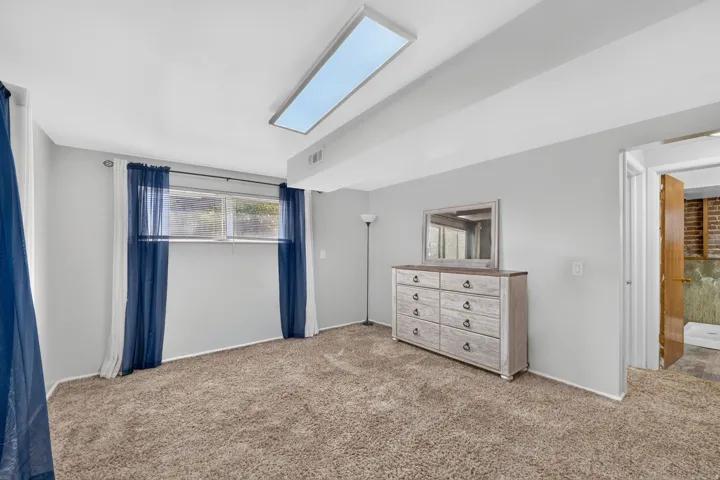 Recessed lighting fixture, textured carpeting, neutral wall paint, and a window with blinds