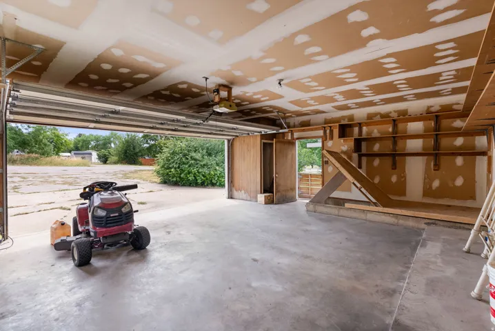 Garage space featuring a concrete floor, built-in shelving, and a side access door