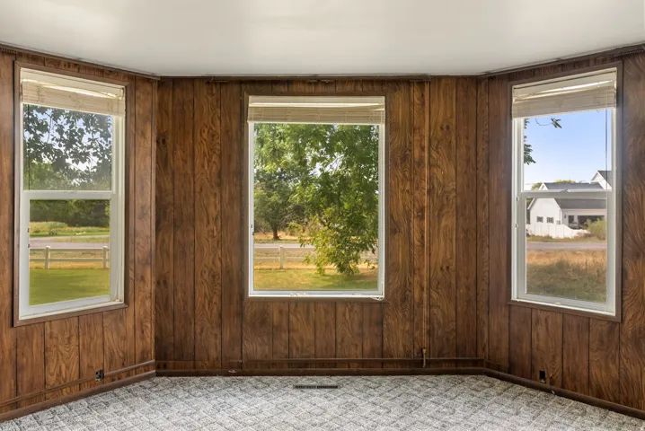 Wood-paneled room with three large windows and carpet flooring