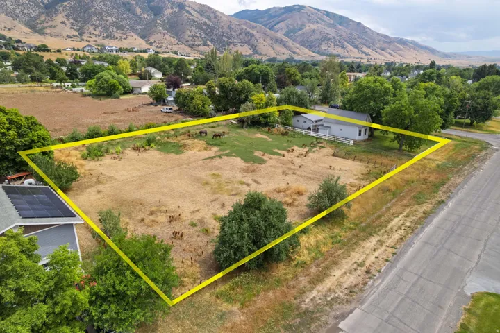 Expansive lot with partial fencing, mature trees, and mountain scenery