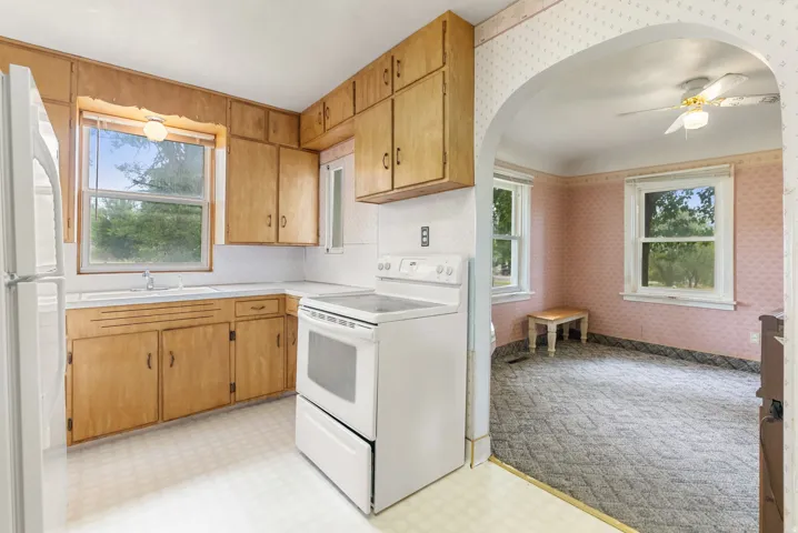 Kitchen featuring light wood cabinetry, white countertops, a white electric range, and a white refrigerator
