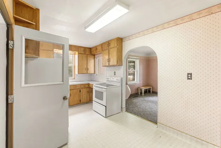 Kitchen featuring wood cabinetry, white countertops, vinyl flooring, and a white electric range