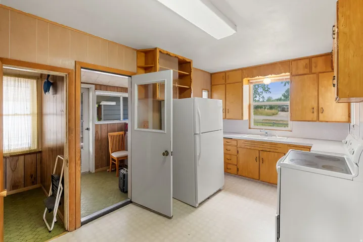 Kitchen featuring wood-finish cabinetry, a window-mounted sink, and a white countertop