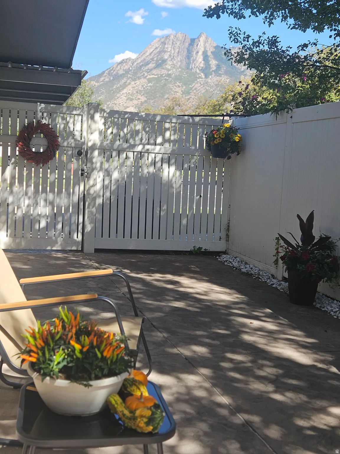 Paved patio area with a white privacy fence and a built-in awning