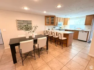 Recessed lighting, wood cabinetry, white countertops, tile flooring, and a kitchen island with seating