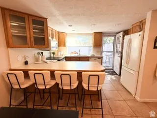 Kitchen featuring wood cabinetry, a counter-height peninsula, integrated appliances, and tiled flooring