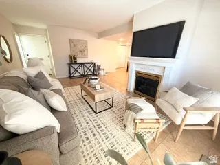 Living area featuring a white mantel fireplace with a dark metal insert, tiled flooring, and a vaulted ceiling
