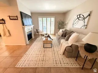 Tile flooring, built-in fireplace, white mantel, sliding glass doors with louvered blinds