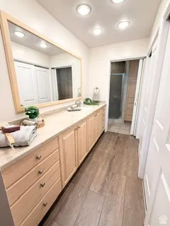 Spacious vanity with light wood cabinetry, a polished countertop, and an integrated sink