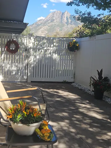 Paved patio area with a white privacy fence and a built-in awning