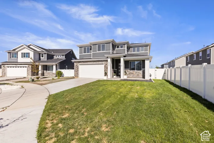 Contemporary exterior with stone facade accents, multi-pane windows, attached garage, and a manicured lawn