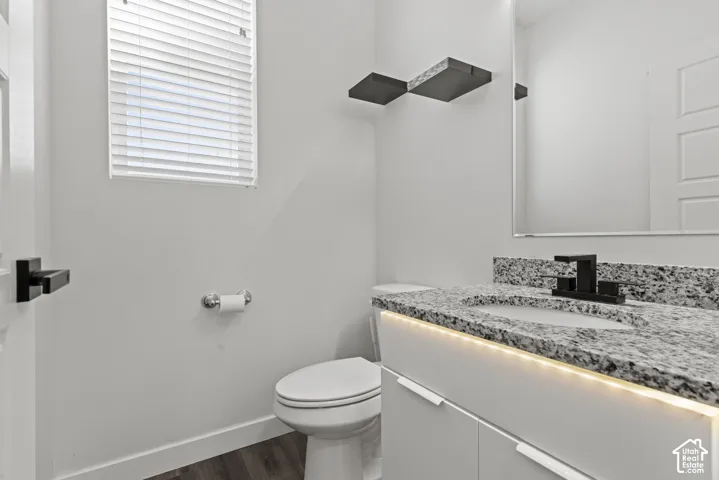 Modern powder room featuring a floating vanity with a speckled countertop, undermount lighting, and a contemporary matte black faucet