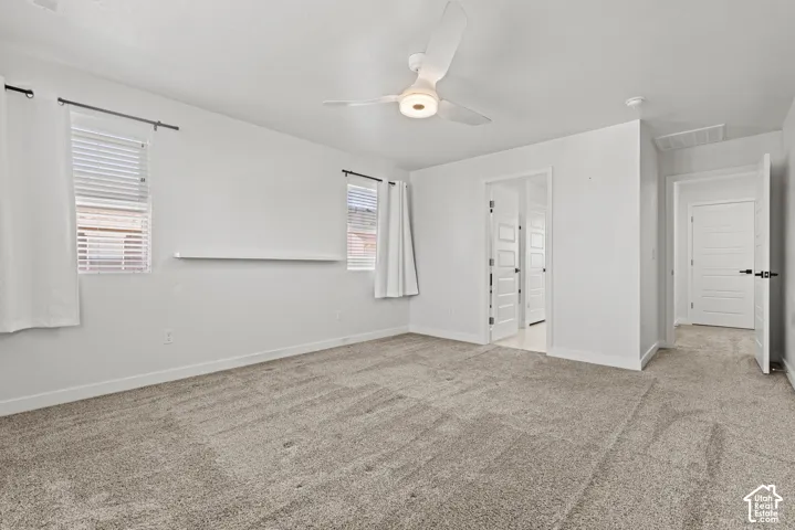 Light-toned carpeting and white walls, two windows with blinds, a ceiling fan with integrated lighting, and white interior doors