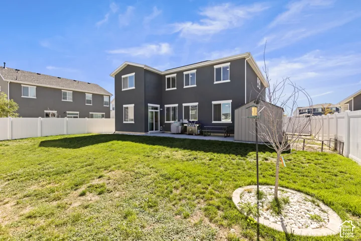 Expansive backyard featuring a manicured lawn, a privacy fence, and a storage shed