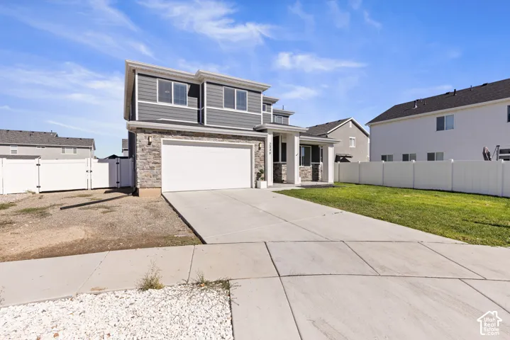 Contemporary exterior with stone accent siding, attached two-car garage, concrete driveway, and a front porch with white columns