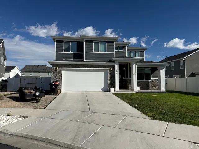 Two-story residence featuring a partial stone facade, a two-car garage, and a covered front entry