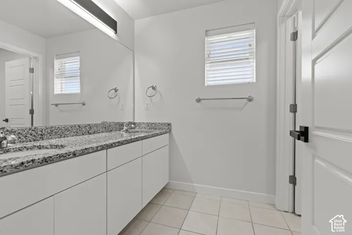 Double vanity with dual undermount sinks, granite countertop, and white cabinetry