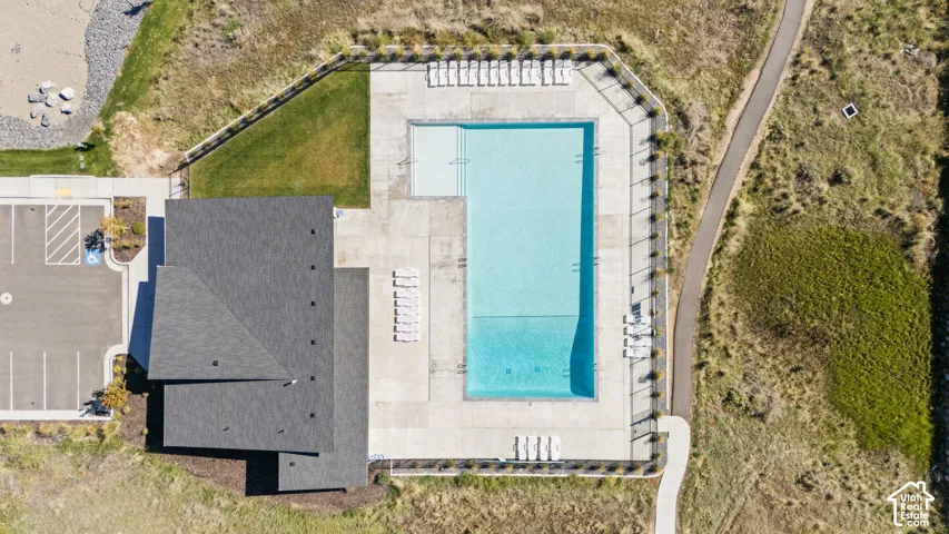 Outdoor swimming pool with integrated wading area, surrounding concrete deck, adjacent paved pathway, and nearby parking area