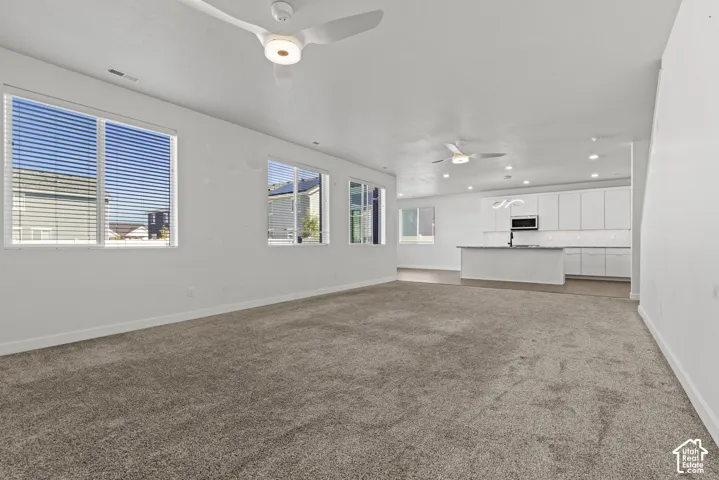 Open-concept living space with multiple windows, recessed lighting, and ceiling fans