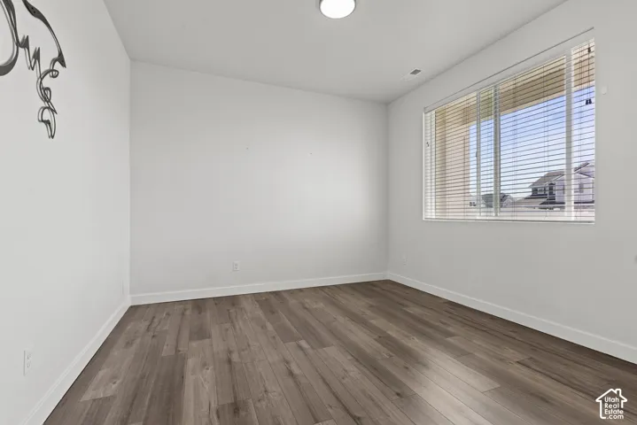White walls, wood-finish flooring, and a window with blinds