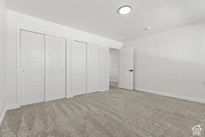 Light gray carpeting, white walls, and a white interior door with matte black hardware