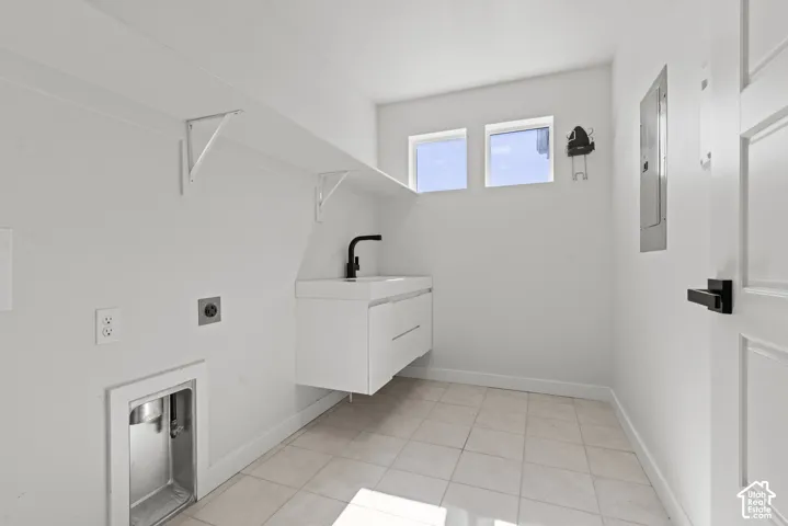 Laundry area featuring a floating white vanity with a black faucet, built-in shelving, and two upper windows