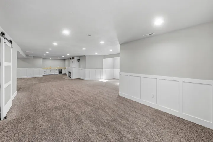 Spacious room featuring carpet flooring, built-in fireplace, and wainscoting