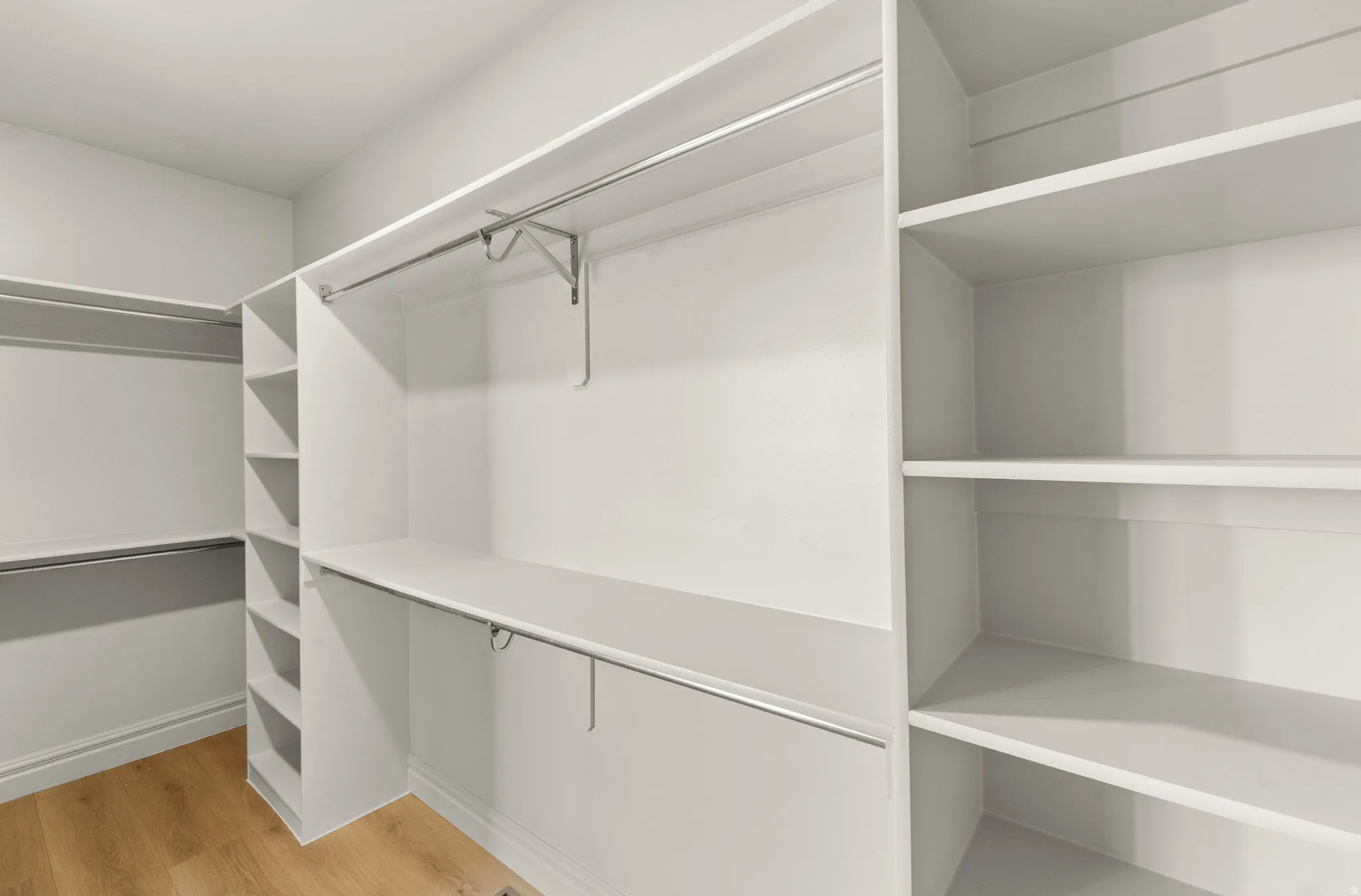 White built-in closet system featuring multiple hanging rods, shelving, and cubby storage