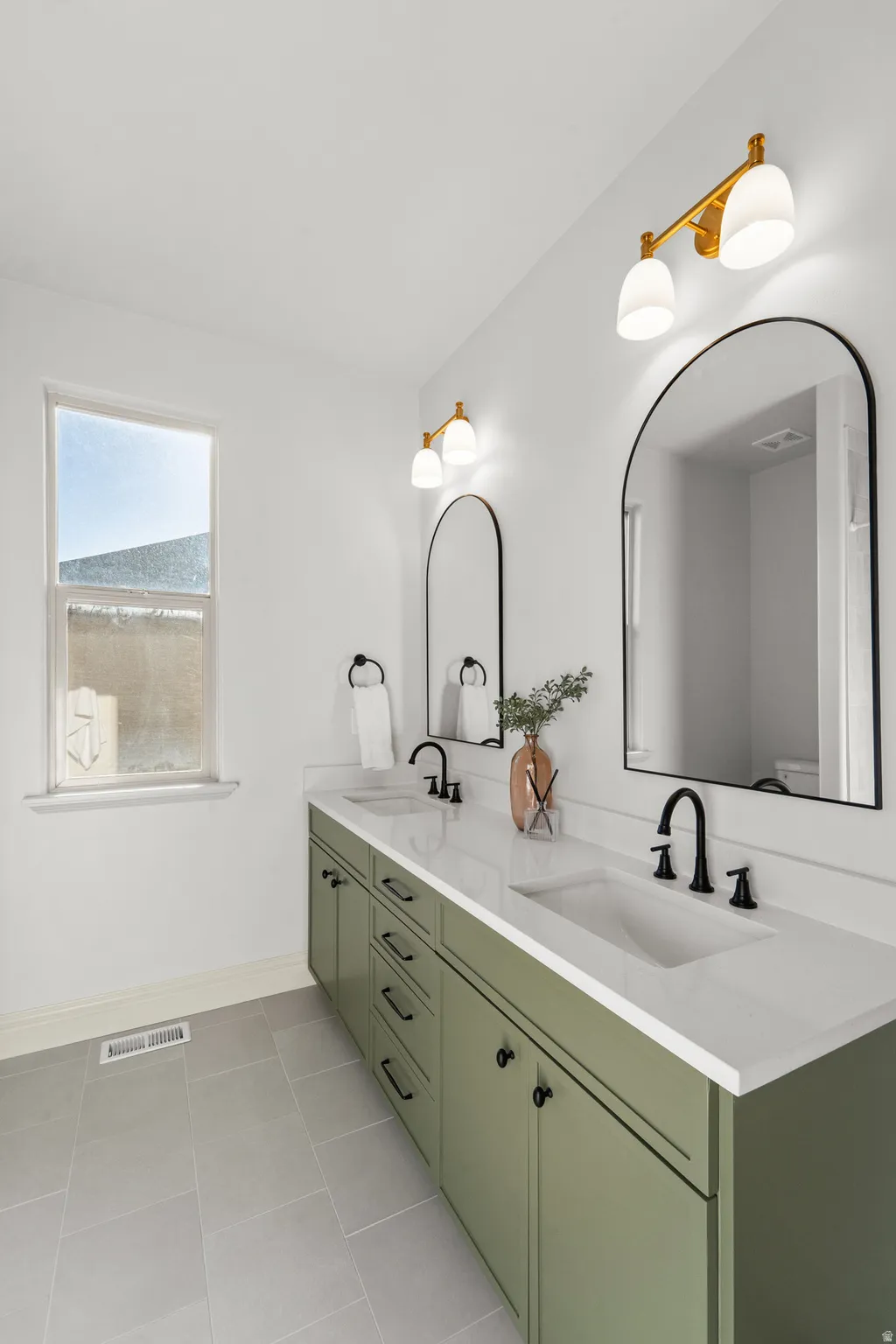 Dual vanity with a white countertop and integrated sinks, matte black faucets, and green cabinetry