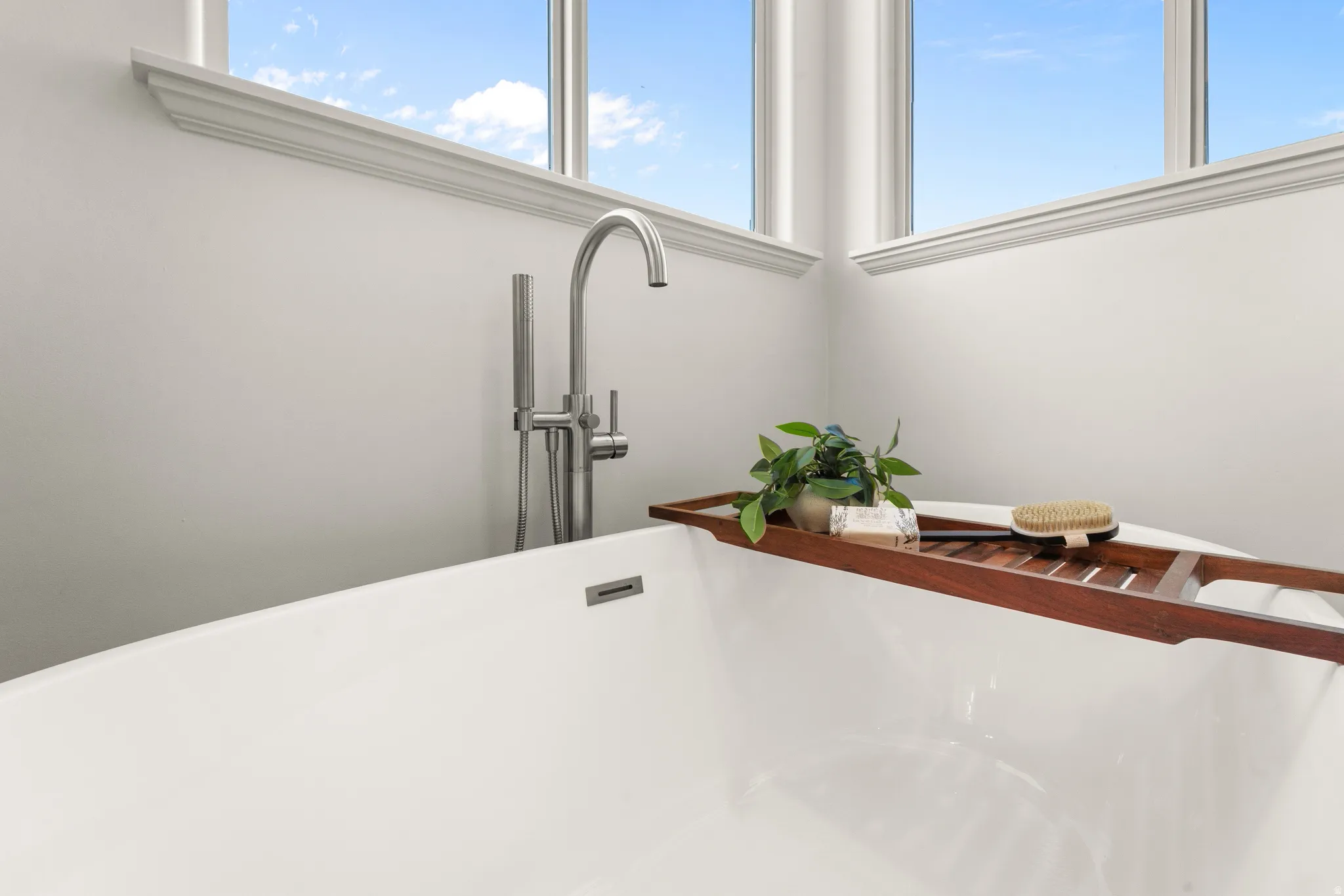 Freestanding soaking tub with a brushed nickel floor-mounted faucet and handheld shower sprayer