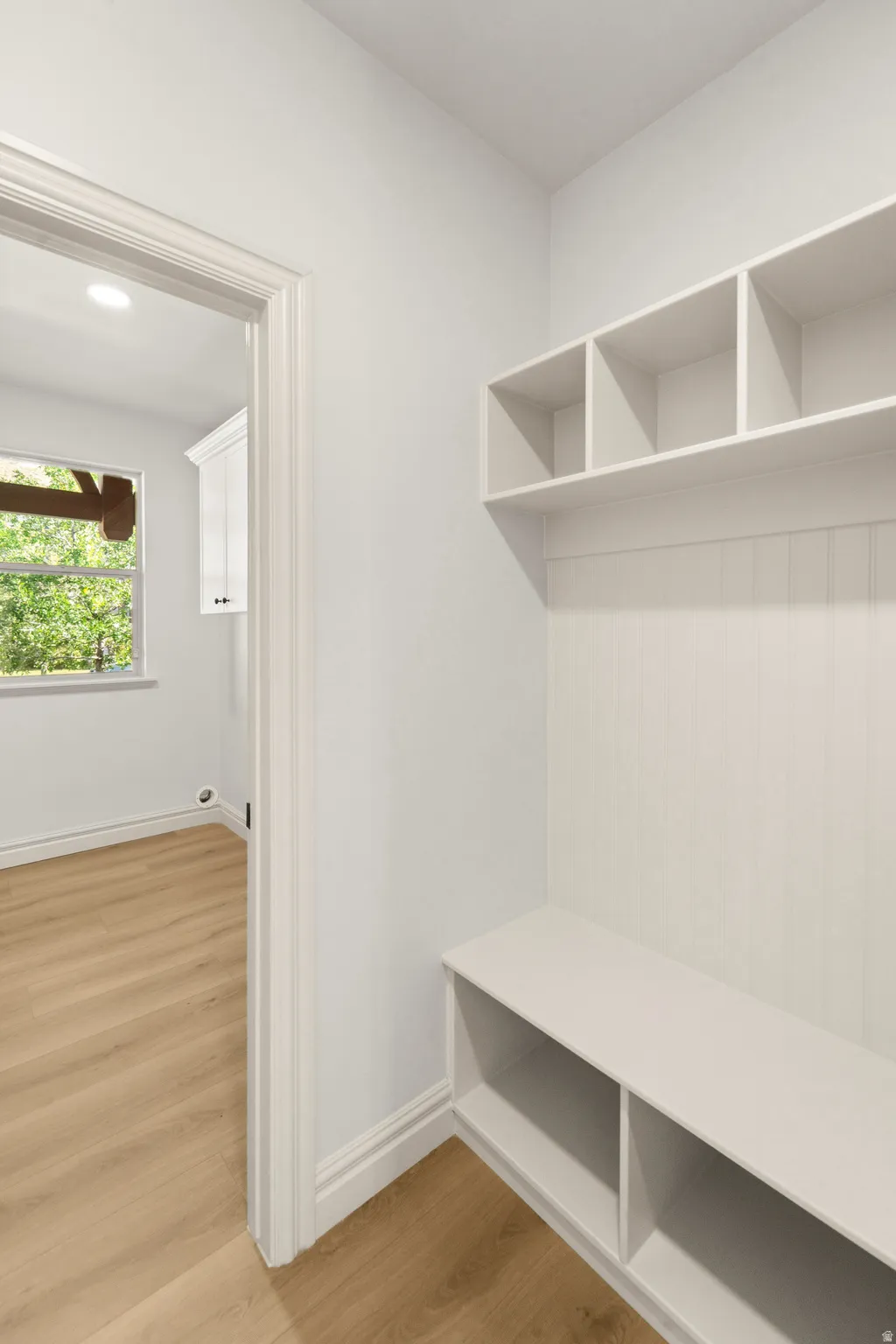 Built-in storage bench with open shelving, beadboard backing, and wood-finish flooring