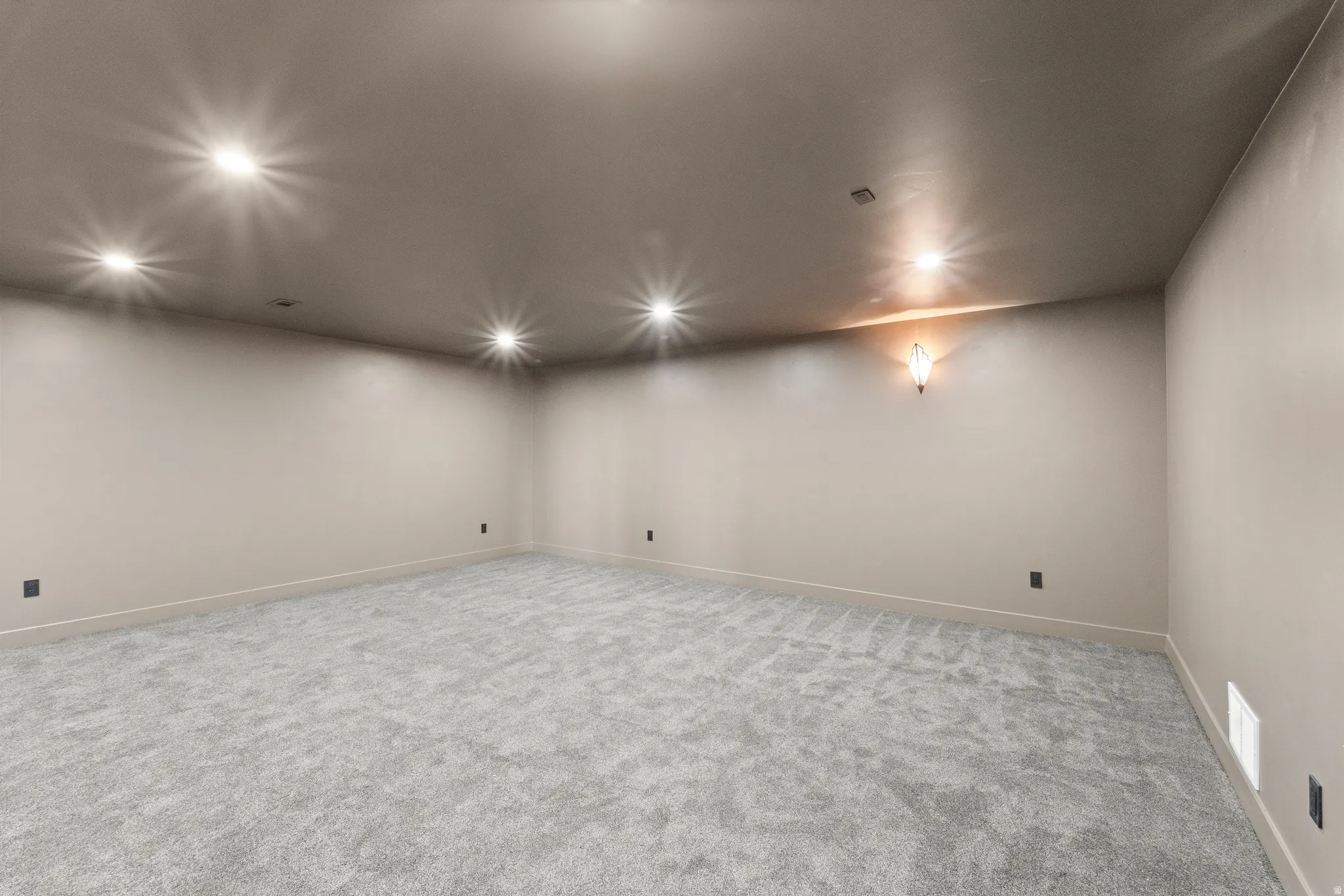 Recessed ceiling lights, neutral wall color, wall sconce, light gray carpet flooring, and white trim