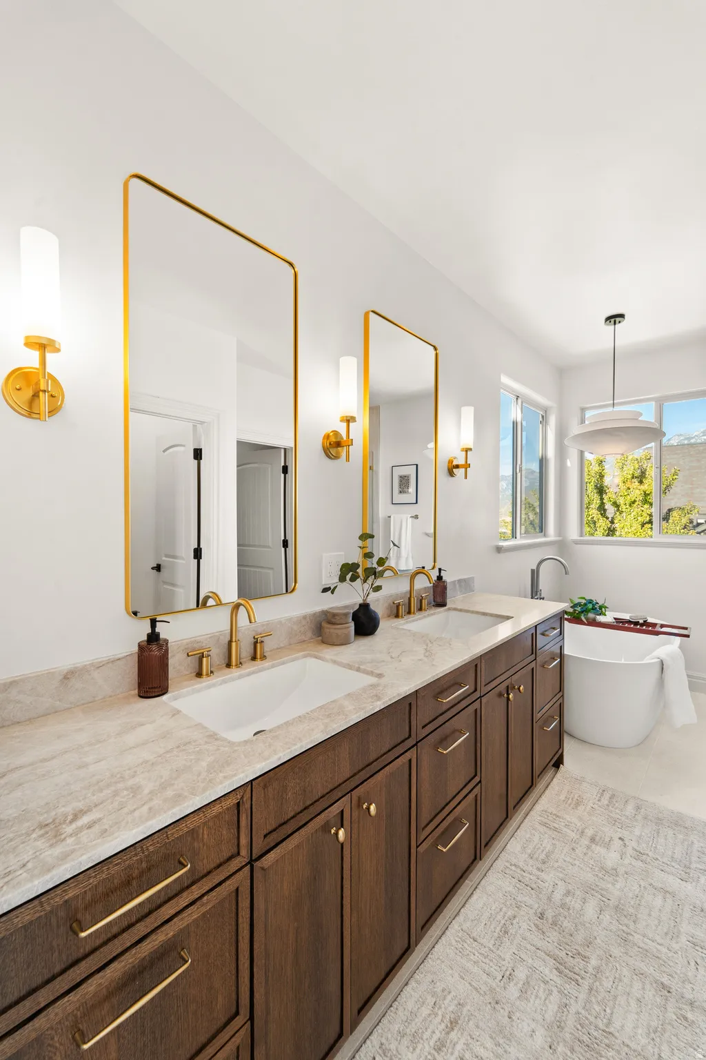 Dual vanity with undermount sinks, gold-finish hardware, and a freestanding soaking tub