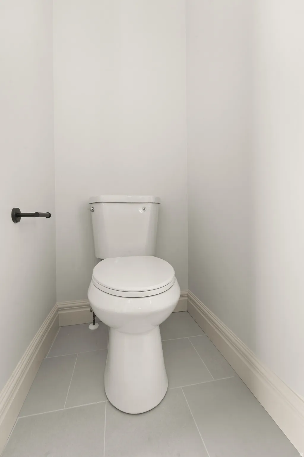 White toilet with gray tile flooring and white trim