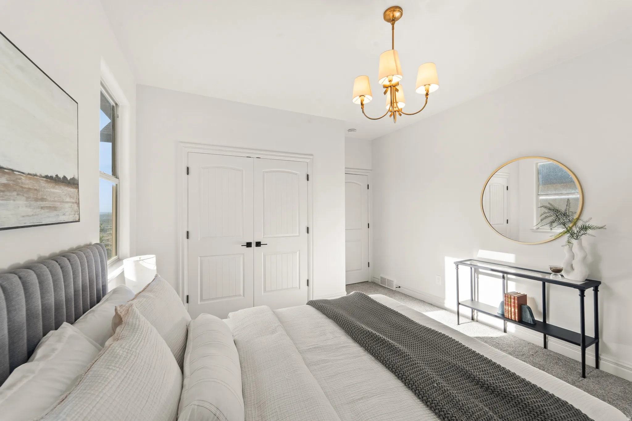 White walls with a gold-finish chandelier, arched double doors, and a window providing natural light