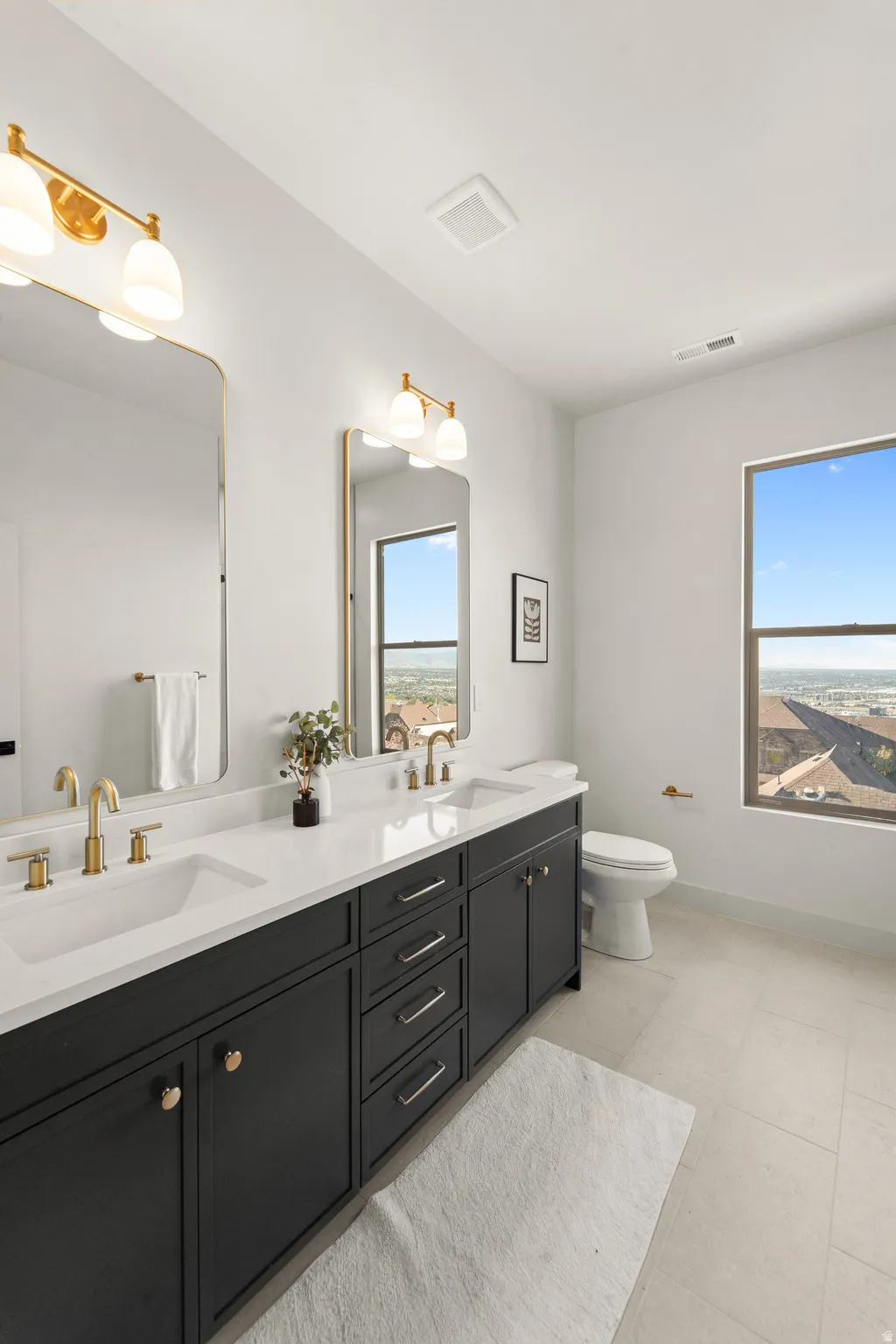 Dual sink vanity with dark cabinetry, white countertops, and gold-finish hardware