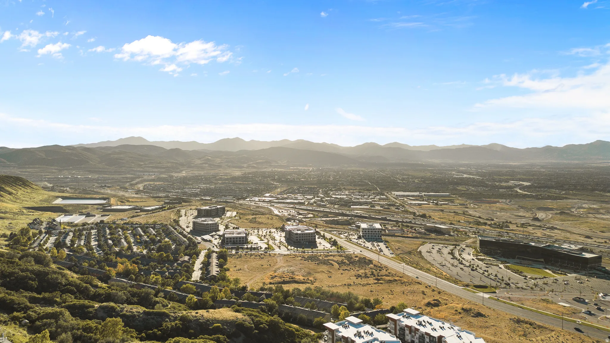 Expansive landscape featuring distant mountains, a developed urban area, and multiple commercial buildings