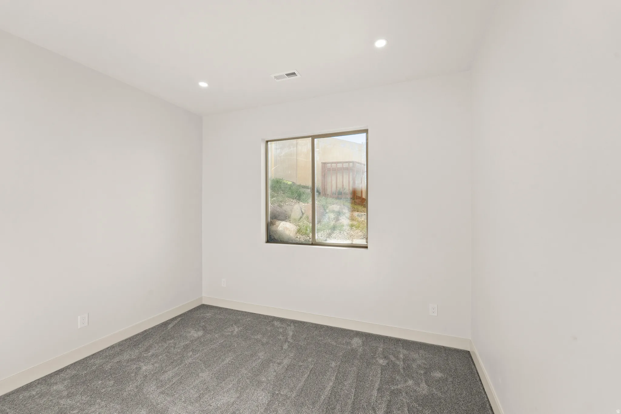 Recessed lighting, light-toned walls, and grey carpeting
