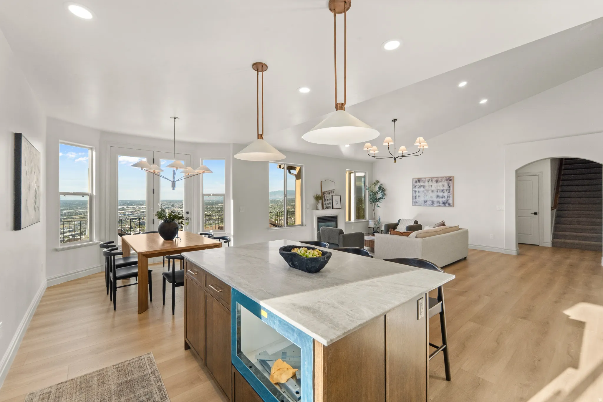 Kitchen island with light-toned countertop, wood-finish flooring, recessed lighting, and a dining area with multiple windows