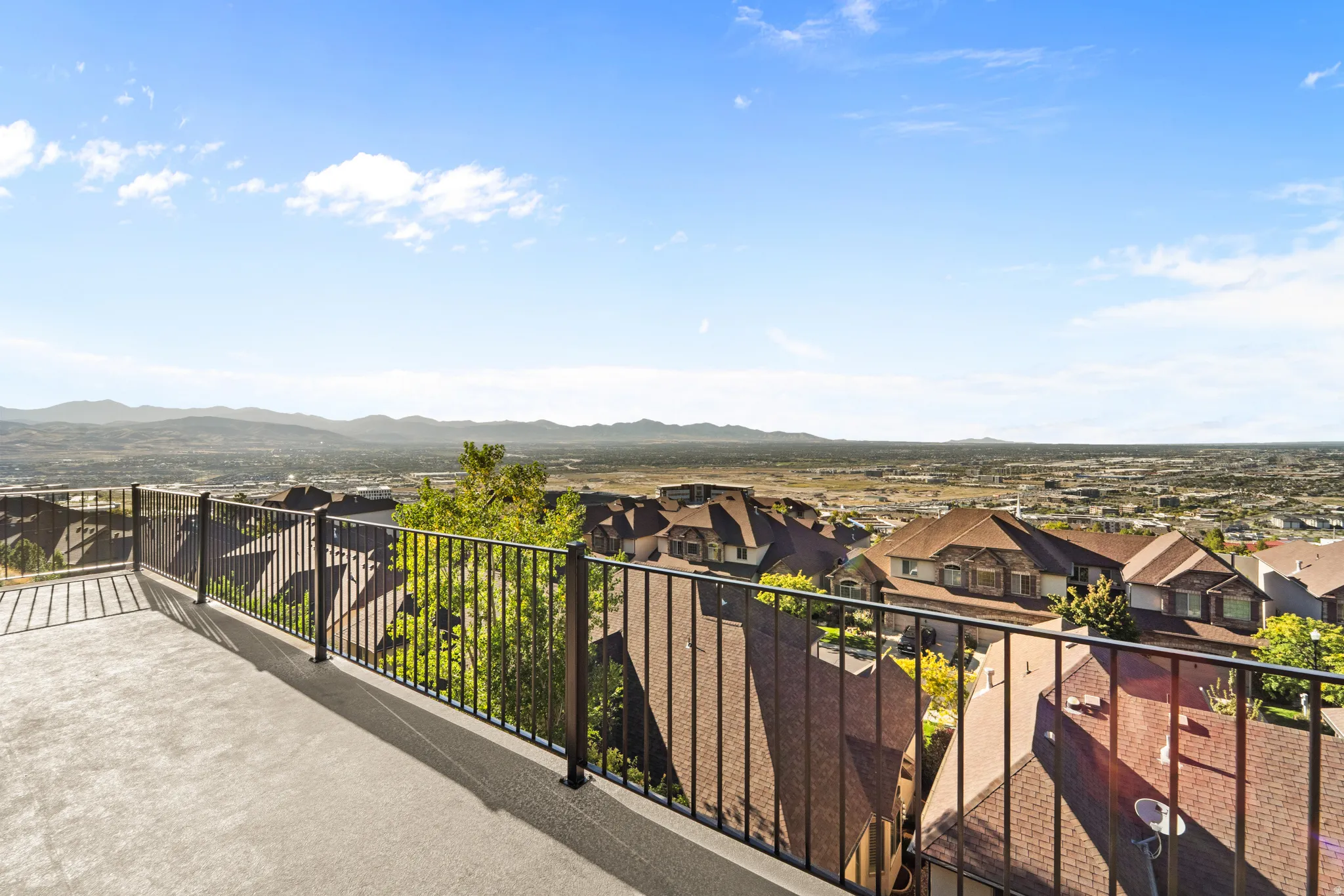 Expansive outdoor terrace featuring metal railings and a distant mountain backdrop