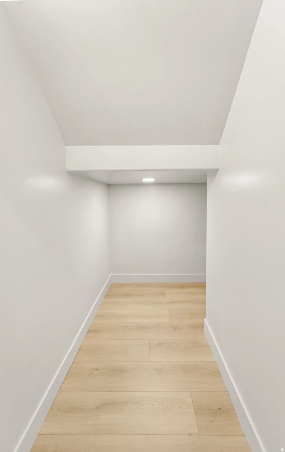 Recessed ceiling lighting, wood-finish flooring, white walls, and bright white trim