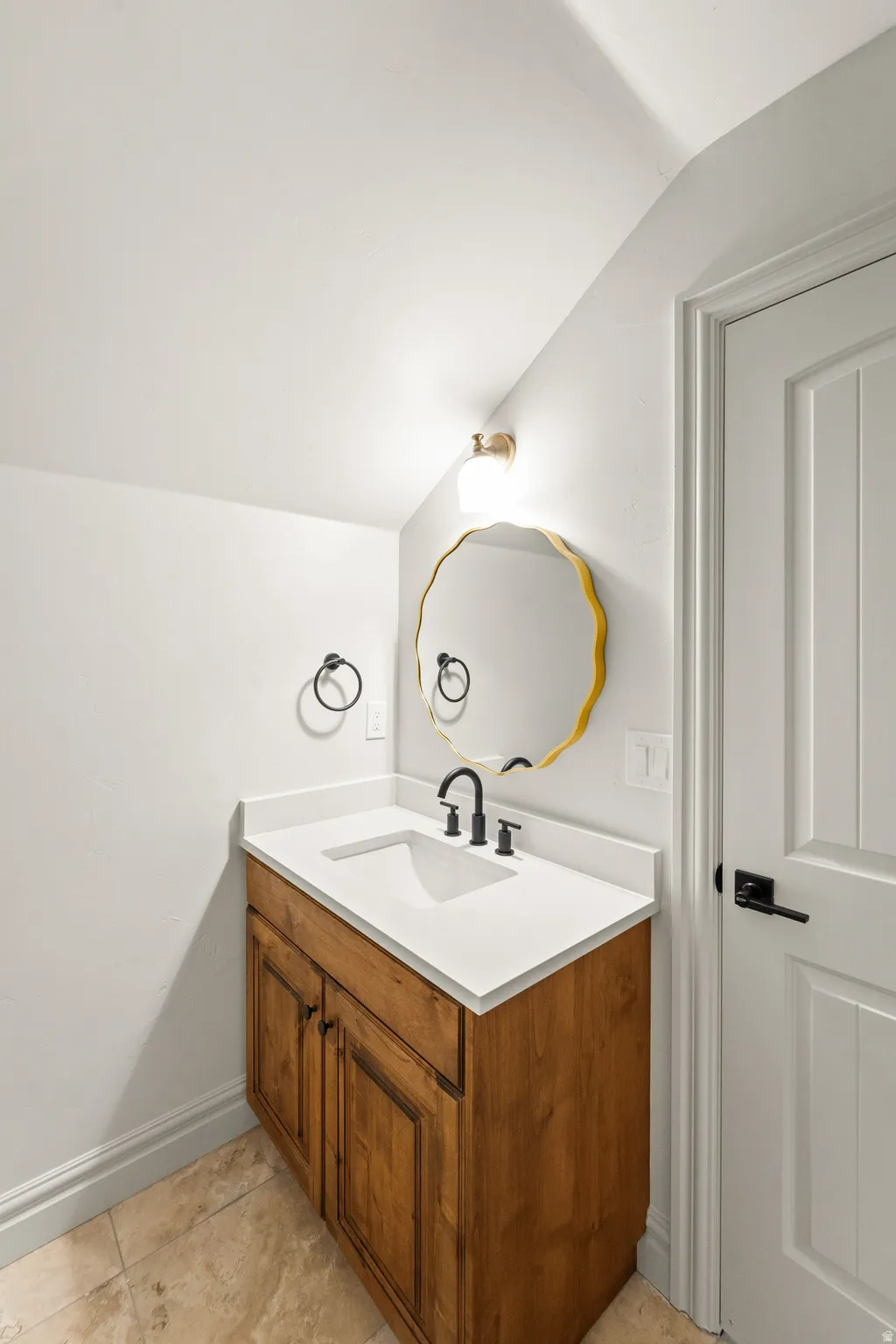 Wood-finish vanity with white countertop, integrated sink, and matte black faucet