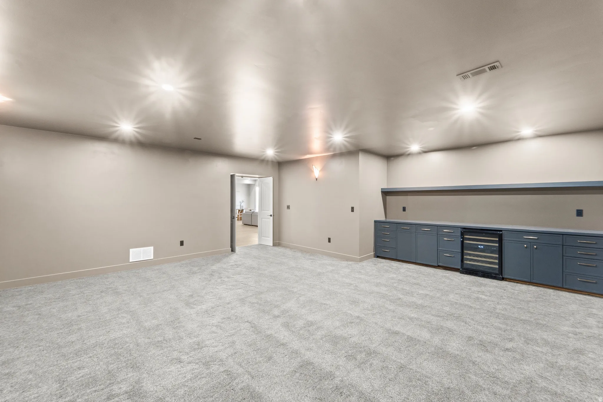 Spacious room featuring recessed lighting, plush carpeting, built-in cabinetry, and integrated beverage refrigeration
