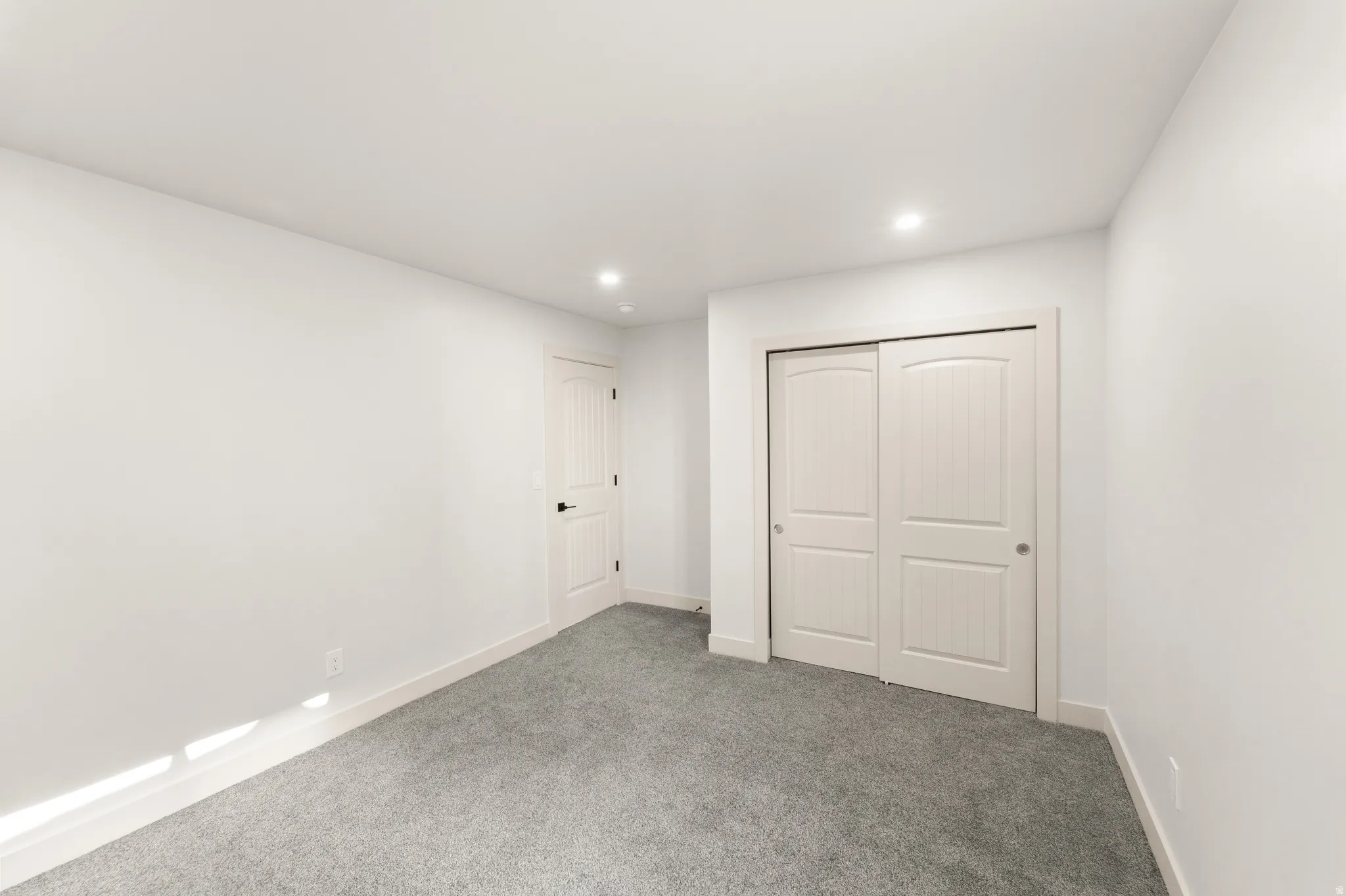 Recessed lighting, light gray carpeting, white walls, white paneled doors, and white trim